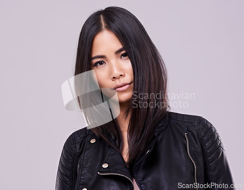 Image of Asian woman and fashion with jacket in confidence on studio, style and casual in grey background. Portrait, female person and trendy with leather top, clothes and outfit for streetwear and gen z