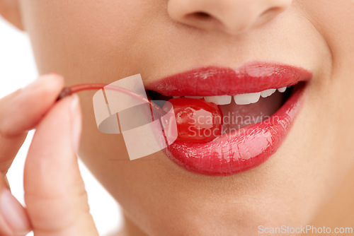 Image of Woman, mouth and bite with cherry, red lipstick or cosmetics for nutrition on a white studio background. Closeup of person, teeth or natural organic fruit with makeup or gloss for diet, fiber or glow