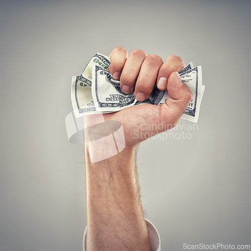 Image of Closeup, hand and money for finance, greed and capitalism for business on grey background in studio. Fist, cash and dollar to invest, pay or loan for bid opportunity, trading and financial market