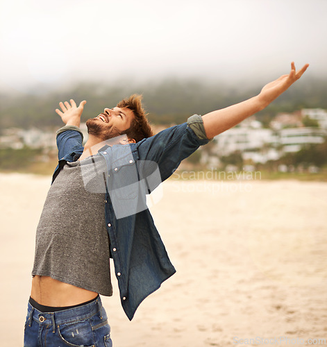 Image of Happy man, beach and freedom with hands out for travel, adventure or outdoor sightseeing in nature. Excited male person with smile in satisfaction or happiness for holiday weekend on the ocean coast