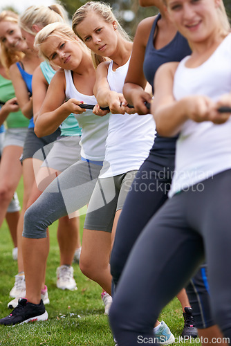 Image of Team, women and friends in tug of war with group, strong and balance with pull for challenge on field. People, exercise and training with rope for games, contest or competition with muscle on grass