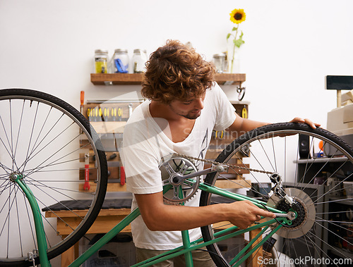 Image of Small business, startup and bike repair with man mechanic in workshop for service or maintenance. Entrepreneur, handyman or technician working on bicycle to fix chain, gear and wheel for occupation