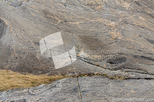 Image of Close-up view of textured rock surface with subtle grass accents