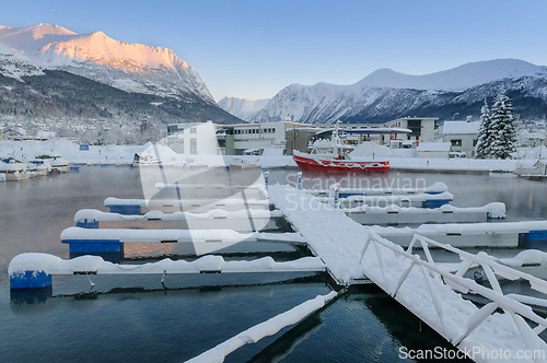 Image of Winter morning at a snow-covered dock with a red boat in a mount