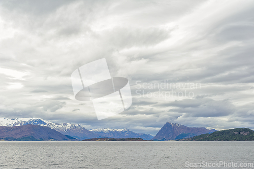 Image of Majestic snow-capped mountains overlooking the serene sea under 