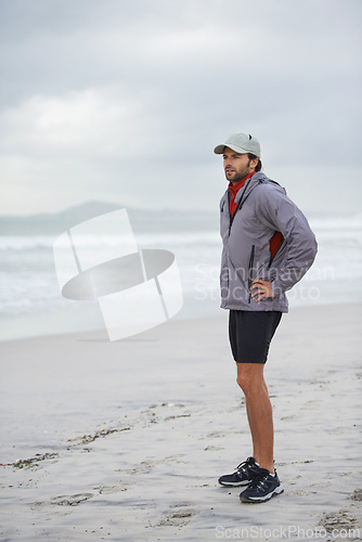 Image of Fitness, break and man thinking at a beach after training, running or winter morning cardio in nature. Workout, recovery and male runner at the sea for sports rest, breathing or body wellness routine