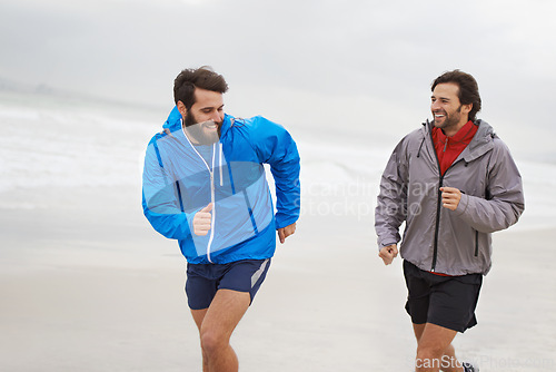 Image of Laugh, men and running on beach, sand and fitness for wellness and gym wear on ocean coast workout. Male athletes, jog and training for seaside, health and outdoor for sport and exercise together