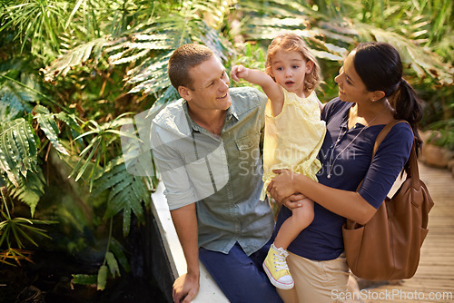 Image of Happy family, child and pointing at zoo with tourist for sightseeing, travel or tour on trip. Father, mother and little girl showing direction, guide or exhibit to explore together in outdoor nature