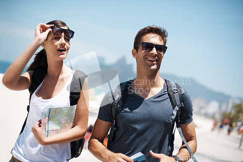 Image of Couple, tourist and smile with map for direction on vacation, trip and happiness in Brazil. Relationship, holiday and bonding at beach for summer with adventure and travel for tour and break.