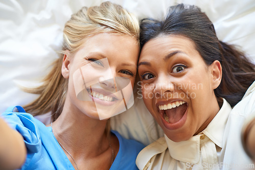 Image of Women, selfie and smiles by friends on bed for profile picture, app and social media network for fun. Diverse, young and excited together in room for crazy and silly memories to bond for friendship