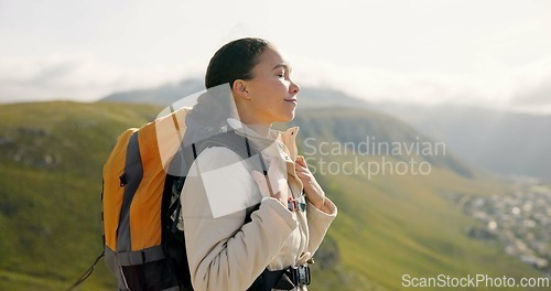 Image of Young woman, trekking on mountains and breathing fresh air for outdoor wellness, fitness and health. Happy person in wind with backpack and hiking in nature on a hill for adventure, travel or journey