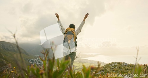 Image of Person, mountain top and freedom or celebration of hiking goals, travel or trekking adventure in nature. Back of hiker or winner in backpack and arms up for success, achievement or excited on a cliff