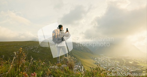 Image of Woman, trekking and video recording on mountains in adventure, wellness and health with nature and cityscape. Person with backpack and hiking photography on green hill, travel or eco friendly journey