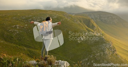 Image of Woman, mountain top and freedom, trekking goals, celebration or travel achievement in nature adventure. Person or winner in backpack with arms up for hiking success, energy and yes on a cliff or rock