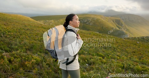 Image of Woman, hiking on mountains and breathing fresh air for outdoor wellness, fitness and health in nature. Happy young person in wind with backpack and trekking on a hill for adventure, travel or journey