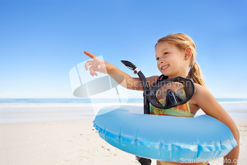 Image of Girl, smile and goggles for swimming at beach, pointing and equipment for water on holiday. Female person, child and happy on tropical vacation in outdoors, inflatable and blue sky for mockup space