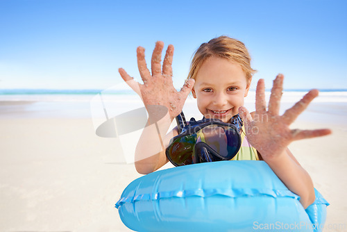 Image of Girl, portrait and hands for swimming on sand, beach and goggles or inflatable donut on holiday. Female person, child and happy on tropical vacation in outdoors, ocean and blue sky for mockup space