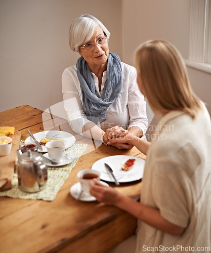 Image of Mother, daughter and home with holding hands in table on lunch for bonding, support and visit. House, family and tea with food for conversation on break, leisure and happiness for coffee and care.