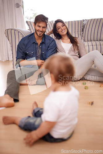 Image of Family, couple and smile in lounge with toddler for growth, development and bonding on floor. Parents, caregivers and happy with little boy or child in home for activities, games and playing