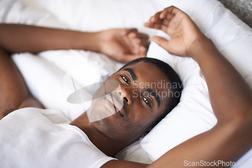 Image of Black man, portrait and morning with bed in relax for wakeup, comfort or resting on duvet or sheets at home. Face of African male person lying awake in bedroom with pajamas for weekend at the house