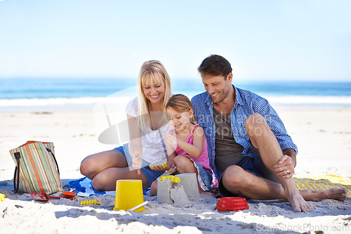 Image of Mom, dad and girl with sandcastle at beach on vacation with care, learning and building on holiday in summer. Father, mother and daughter with plastic bucket with sand for game, play and happy by sea