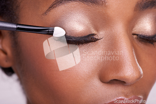 Image of Black woman, closeup of face and brush for eyeshadow with makeup, beauty and lashes on pink background. Skin glow, cosmetics product and tools for cosmetology, shimmer or glitter with shine in studio
