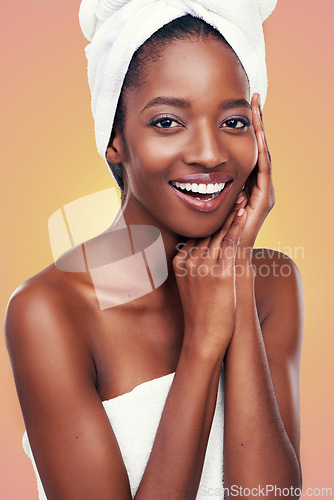 Image of Hair towel, portrait and black woman in studio for skincare, wellness or body care on orange background. Beauty, cleaning or hands on face of African female model with cosmetic, shine or glowing skin