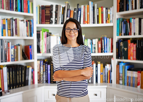 Image of Woman, portrait and confidence by bookshelf in home with books for reading, learning and knowledge in living room. Professor, face or happy by house library with magazine, journal or study collection