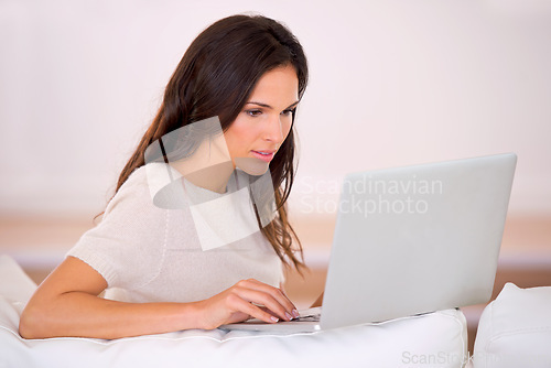 Image of Woman, laptop and typing on sofa for remote work from home with thinking, idea or writing article. Person, girl or writer on computer in lounge with research for story, blog or report at media agency