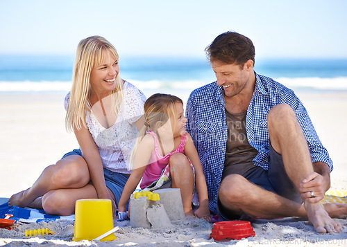 Image of Mom, dad and girl with sandcastle by ocean on vacation with care, learning or building on holiday in summer. Father, mother and daughter with plastic bucket at beach for game, blanket or happy by sea