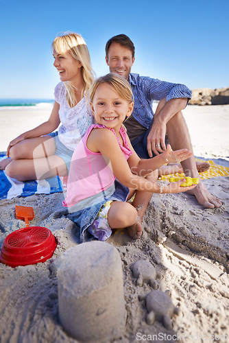 Image of Parents, child and sandcastle in portrait at beach, blanket and excited with smile for holiday in summer. Father, mother and daughter with family picnic by ocean for vacation with love in sunshine
