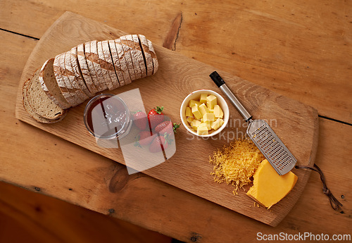 Image of Breakfast, board and cheese with jam, bread and fresh strawberry for diet, nutrition and gourmet morning snack. Food, fruit and high angle of sweet, savory and delicious rustic brunch on charcuterie.