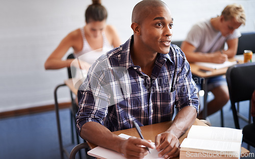 Image of Black man, student and writing with book in classroom for studying, reading or summary at university. African male person or young academic writer with notebook for assignment, test or exam at campus