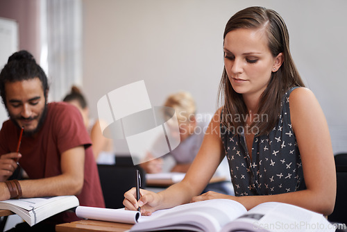 Image of Woman, student and writing in classroom for studying, reading or summary in book at university. Female person or academic writer taking notes for assignment, test or literature exam on desk at campus