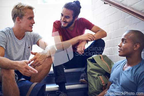 Image of Happy man, student and friends talking on stairs with group for conversation, social interaction or chat at campus. University people or male person with smile on staircase for discussion at college