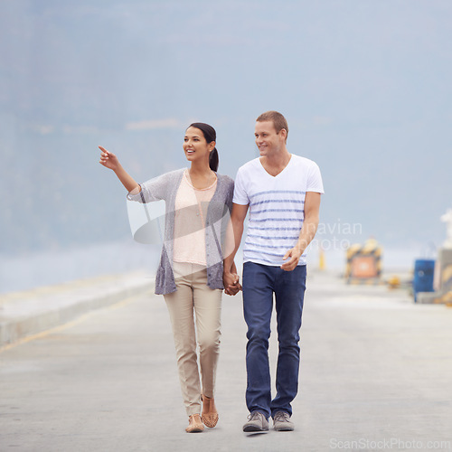 Image of Couple, ocean and happy in boardwalk on vacation for honeymoon, love and relax in New Zealand. Pointing, relationship and beach for travel on holiday with trip for support, bonding and holding hands