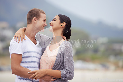 Image of Love, romance and dating for couple at beach for leisure, bonding or vacation. Partners, mates and relationship with smile and hug for kiss and affection against blurred background and mockup