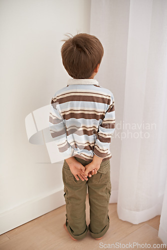 Image of Child boy, trouble and time out for bad behaviour, discipline and parenting in family home. Punishment, small kid or son in corner of living room, house and childhood development for toddler