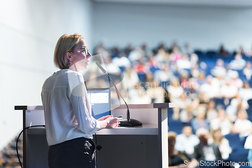 Image of Female speaker giving a talk on corporate business conference. Unrecognizable people in audience at conference hall. Business and Entrepreneurship event.