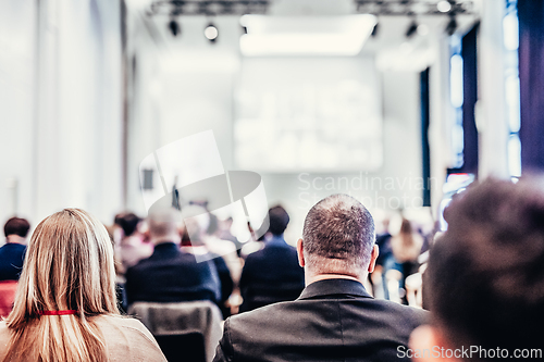 Image of Speaker giving a talk in conference hall at business event. Rear view of unrecognizable people in audience at the conference hall. Business and entrepreneurship concept.