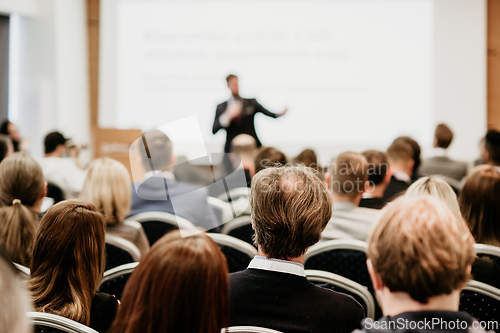 Image of Speaker giving a talk in conference hall at business event. Rear view of unrecognizable people in audience at the conference hall. Business and entrepreneurship concept.