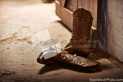Image of Cowboy boots, ranch and style at farm for walking, safety and retro fashion on floor, ground and barn. Shoes, leather product and vintage heel with pattern for steps, western aesthetic or culture