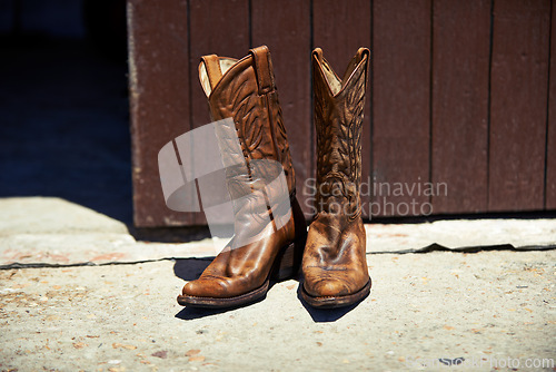 Image of Cowboy boots, ranch and style at farm for walking, safety and retro fashion on floor, ground and barn. Shoes, leather product and vintage heel for steps, outdoor or aesthetic for agriculture in Texas