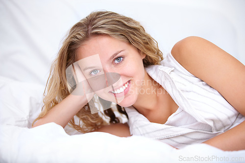 Image of Female person, smile and portrait while laying on bed to relax, bedroom and closeup with happiness and happy. Woman, wavy hair and beauty while calm, peace and confident while inside home in linen