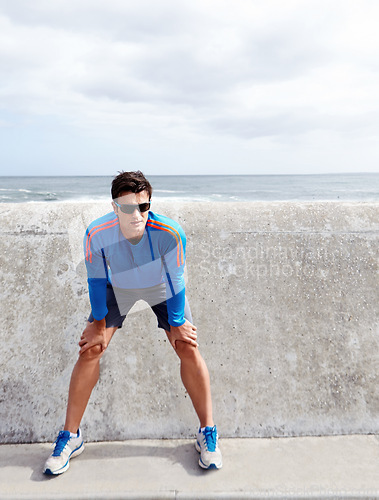 Image of Man, ocean and stretching for fitness with confidence for workout, health and wellbeing in Chicago. Male person, sportswear and active as runner with exercise at beach and committed with sunglasses.