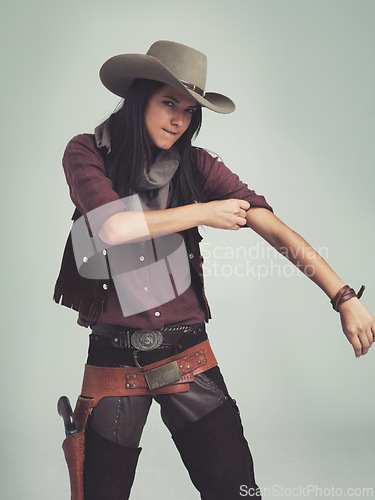 Image of Tough, woman and cowboy portrait with fashion outfit, in Texas as cowgirl and leather belt. Angry face, rolling up sleeve and ready to fight with gun in holster and comic on a grey background studio