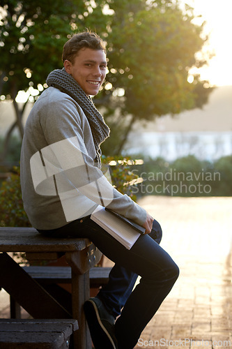 Image of Student, man and outdoor on campus with book in smile, study and prepare for exam with revision notes. Portrait, college and academic for assignment with textbook for education and learning.