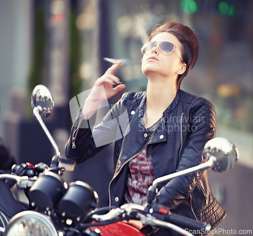Image of Woman, leather and cigarette in city with motorcycle for travel, transport or road trip as rebel. Fashion, street and person smoking nicotine with attitude on classic or vintage bike for journey