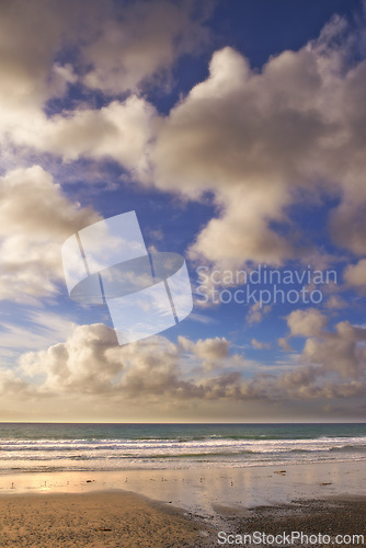 Image of Beach, landscape and ocean at sand with clouds in blue sky on vacation, holiday or summer in California. Sunset, sea and travel outdoor with calm waves, water and horizon in nature or environment