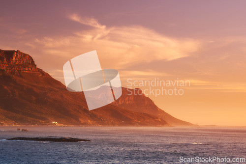 Image of Ocean, sunset and clouds on mountains by blue sky and outdoor travel for vacation in nature. Landscape, sea and sunlight on false bay with calm and seal island in cape town for tourist destination